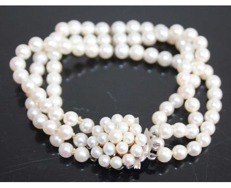 A cultured pearl three-string bracelet, the strung knotted pearls each approx dia.5.2 - 5.4mm, to a white metal flower head c