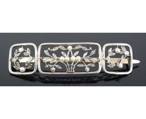 An Art Deco white metal seed pearl and diamond point set panel brooch as a central basket issuing flowers and foliage, the le