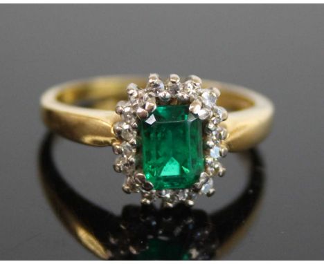 An 18ct yellow and white gold, emerald and diamond octagonal cluster ring, featuring a step cut emerald within a border of 18