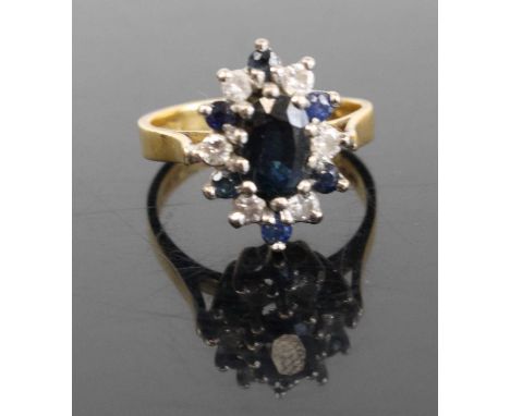 A modern 18ct gold sapphire and diamond flowerhead cluster ring, arranged as a centre oval cut sapphire, measuring approx 7.4