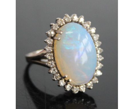 A 9ct white gold, opal and diamond oval cluster ring, comprising a central opal cabochon within a border of 26 single cut dia