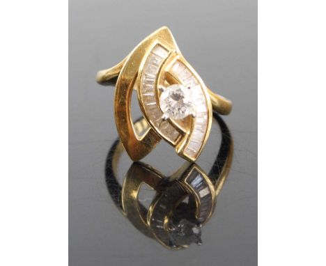 A modern 18ct gold diamond dress ring arranged as a four claw set brilliant, weighing approx 0.3ct within an elliptical surro