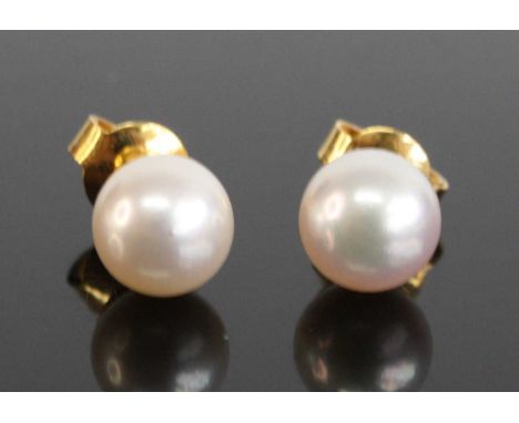 A pair of yellow metal 7.3mm cultured pearl stud earrings, having post and scroll fittings, pearls assessed as silver-white c