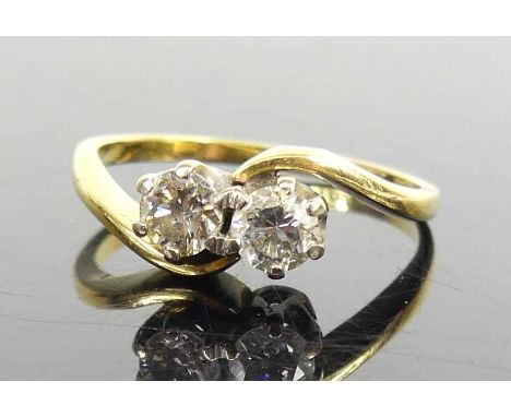 An 18ct yellow and white gold, diamond two-stone crossover style ring, having two round brilliant cut diamonds in claw settin