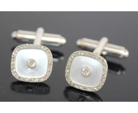 A pair of 9ct yellow and white gold diamond set cufflinks, the shaped square mother of pearl inset settings with a centre dia