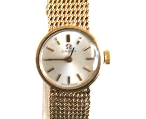 A lady's 9ct yellow gold Omega manual wind wristwatch with round silver baton dial and integral tapered Milanese bracelet wit