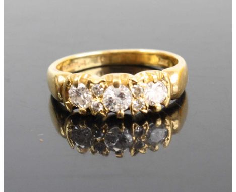 An 18ct gold diamond half hoop ring, arranged as three claw set round brilliants in a line setting each weighing approx 0.18c