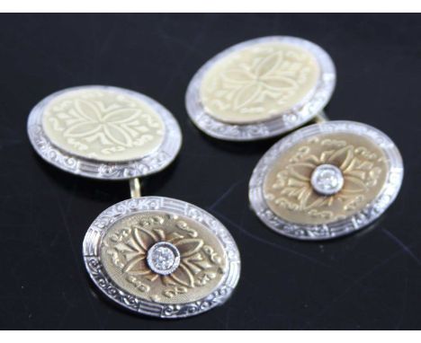 A pair of gent's yellow and white metal diamond set cufflinks, the opposing oval plate having carved and further engine turne