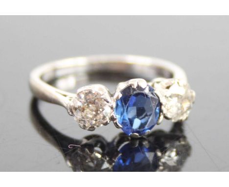 A white metal, sapphire and diamond three-stone ring, featuring a centre oval sapphire with an Old European cut diamond to ei