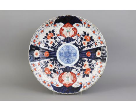 Große japanische Imari Porzellanplatterunde, vertiefte Form mit godronierter Wandung und passig geschwungenem Rand, im Spiege