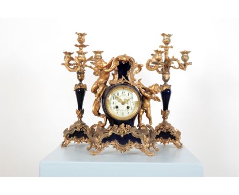 A FRENCH GILT METAL MOUNTED BLUE PORCELAIN CLOCK GARNITUREin the Rococo style, the clock surmounted with cherubs above the fl