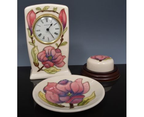 Moorcroft mantel clock, magnolia on an ivory coloured ground, 1994, 16cm and a magnolia paperweight and coaster, the latter b