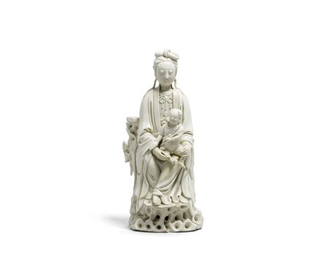 A Dehua porcelain figure of a seated Guanyin with child19th centuryThe figure seated in flowing robes and elaborate jewels up