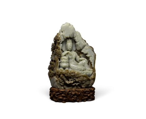 A GREEN AND BROWN JADE GUANYIN GROTTOThe divinity depicted leaning on a fu-lion as she reclines within a shallow cave.12 1/4i