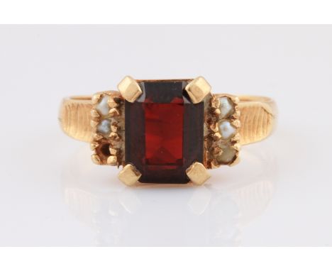 A 9ct yellow gold red stone and pearl seed ring, set with a central emerald cut red stone, measuring approx. 9x7mm, flanked b