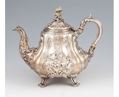 A Victorian silver tea pot of baluster form with repousse floral and scroll design body and handle with domed hinged lid havi