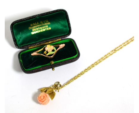 A 9 carat gold Art Nouveau enamel floral brooch, measures 1.6cm by 3.5cm and a carved coral rose pendant, to a leaf motif bai
