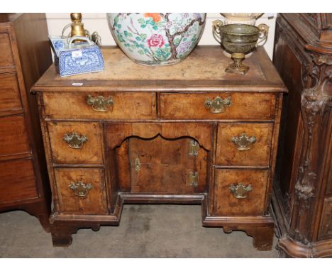 An 18th Century walnut kneehole desk, fitted two drawers above a blind frieze drawer and central recessed cupboard, flanked b
