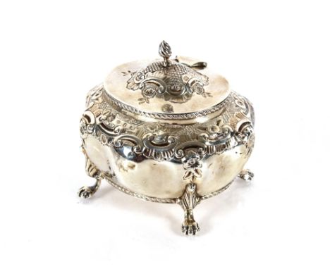 A late Victorian silver tea caddy, the hinged lid surmounted by a flambé finial, body embossed with flower heads and C scroll