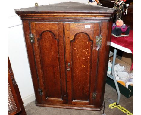 An 18th Century oak hanging corner cupboard, enclosed by a pair of moulded arched panel doors hung to brass H shaped hinges, 
