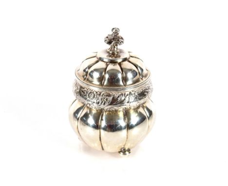 A Victorian silver tea caddy, the domed hinged lid surmounted by a flower finial, foliate chasing to the body on three ball f