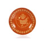 A large antique slipware circular bowl, decorated with a naïve chicken and flowers, 35cm dia.