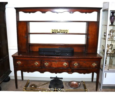 A 18th Century oak dresser, the plate rack flanked by cupboards, three drawers below on a shaped apron and square section tap