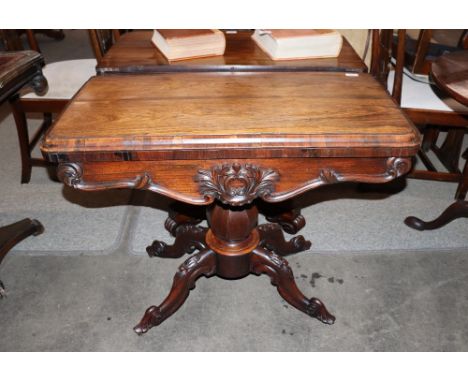 A Victorian rosewood card table, the fold over swivel top raised on an octagonal baluster column and carved quadruple splay t