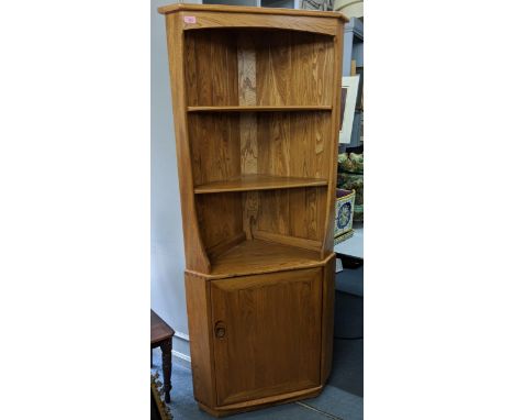A blonde Ercol corner unit with two shelves over a cupboard raised on a plinth Location: 