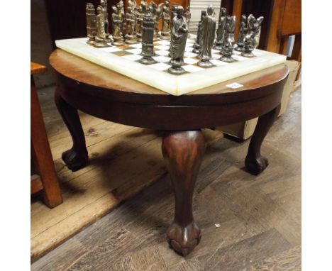 A circular mahogany coffee table standing on claw and ball feet 