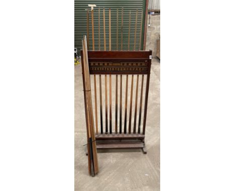 A vintage rack of snooker cues with a collection of additional cues, rack H. 129cm.