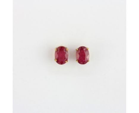 A matching pair of 9ct yellow gold stud earrings set with an oval cut ruby, L. 0.8cm.