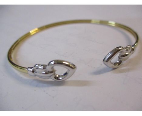 A 9ct gold and silver bangle with heart shaped ends, boxed 