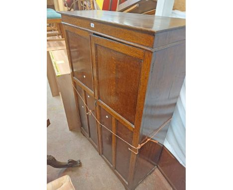 A 1.07m 1920's polished oak wardrobe with shelves, two drawers and hanging space enclosed by a pair of panelled doors, set on
