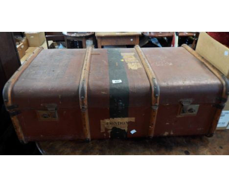A 90cm vintage weather coated tin and cane bound travelling trunk with flanking leather strap handles and various applied shi