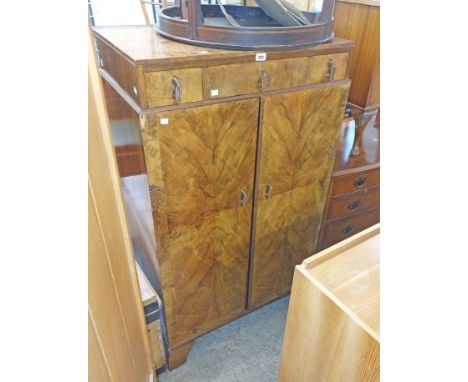 An 84cm 1930's walnut tallboy linen press with three drawers to top and pair of cupboard doors under, set on bracket feet