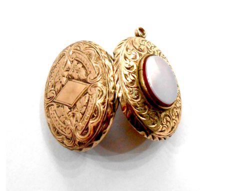 A yellow metal oval locket with chased decoration and central oval agate panel - blank cartouche verso