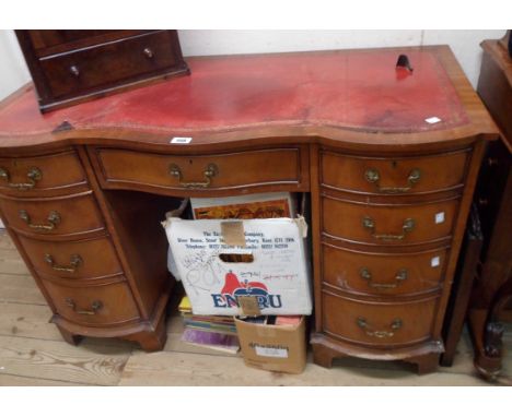 A 1.15m reproduction mahogany serpentine front kneehole writing desk with inset red leather writing surface over central frie