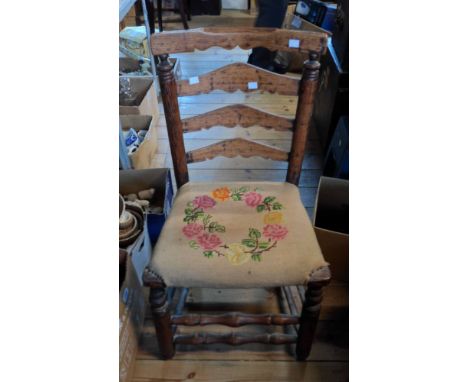 An old rustic oak ladder back dining chair with tapestry upholstered seat