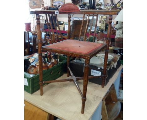 An Edwardian stained wood framed corner elbow chair with upholstered seat panel