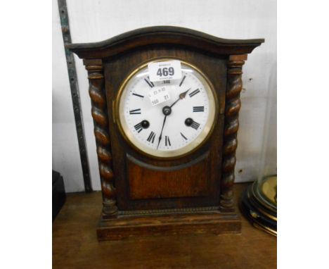 An early 20th Century oak cased mantle clock with flanking barley twist decoration and eight day gong striking movement