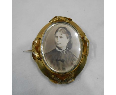 A large late Victorian gilt metal framed swivel brooch with photographic portrait of a bearded gentleman and a lady