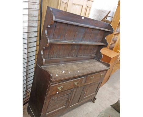 A 1.32m 20th Century stained oak dresser with two shelf open plate rack over two frieze drawers and pair of panelled cupboard