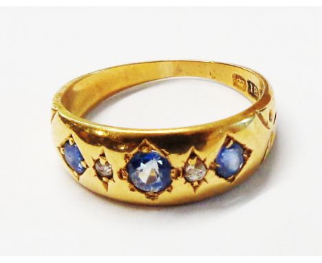 An 18ct. gold gypsy set three stone cornflower blue sapphire and tiny diamond ring - size K