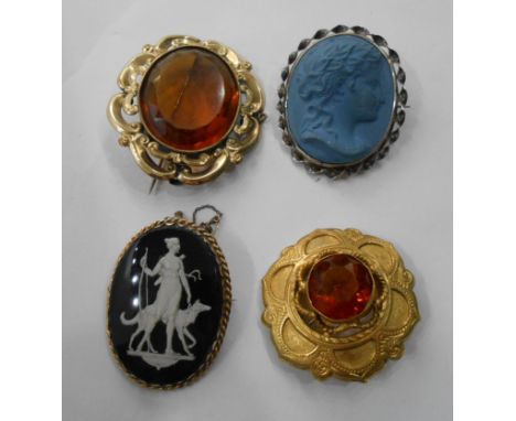 Two large gilt metal brooches, both set with large orange glass stones, also a blue ceramic cameo panel brooch and a gilt fra