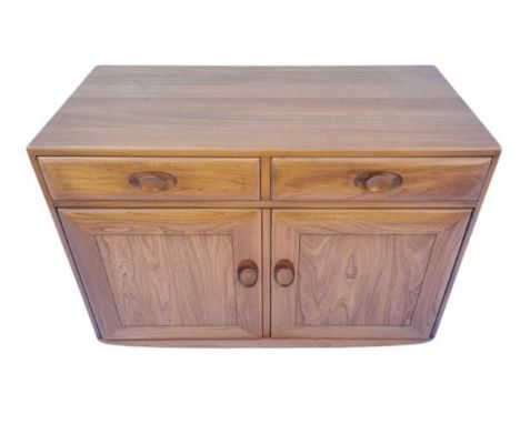 A small elm sideboard by Ercol, having two drawers, one with cutlery tray, over double cupboard doors enclosing a single shel