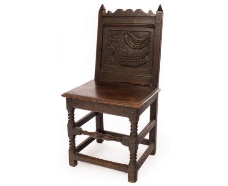 A William &amp; Mary oak chair with solid seat, the panelled back carved with a bird and stylised leaves, on ring turned legs