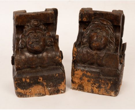 A pair of 17th Century architectural oak corbels carved as the heads of a gentleman and a lady, with scrolling sides, 24cm hi