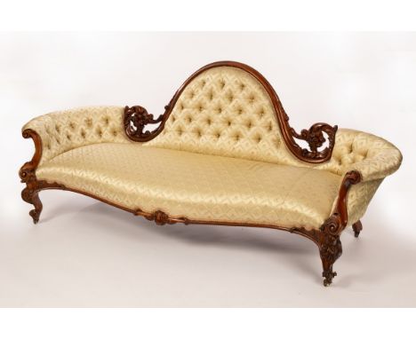 A Victorian sofa with central moulded arch, upholstered back and concave ends, carved and pierced scroll and floral frame on 
