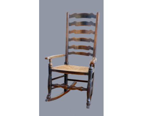 An 18th century oak ladder back rocking chair, with rush seat 